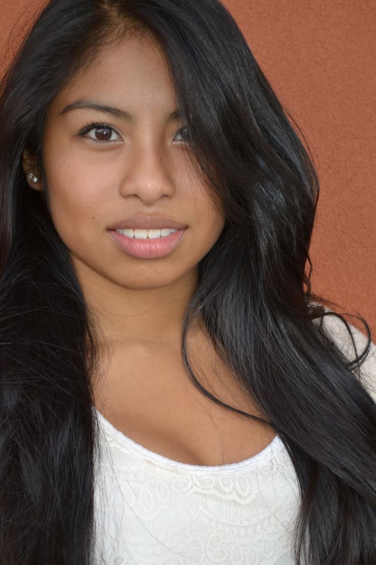 Woman with long black hair wearing a white lace top and earrings