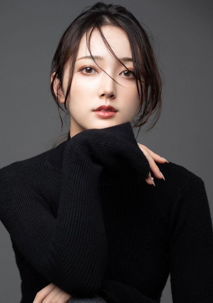 Woman with dark hair wearing a black turtleneck in a studio setting