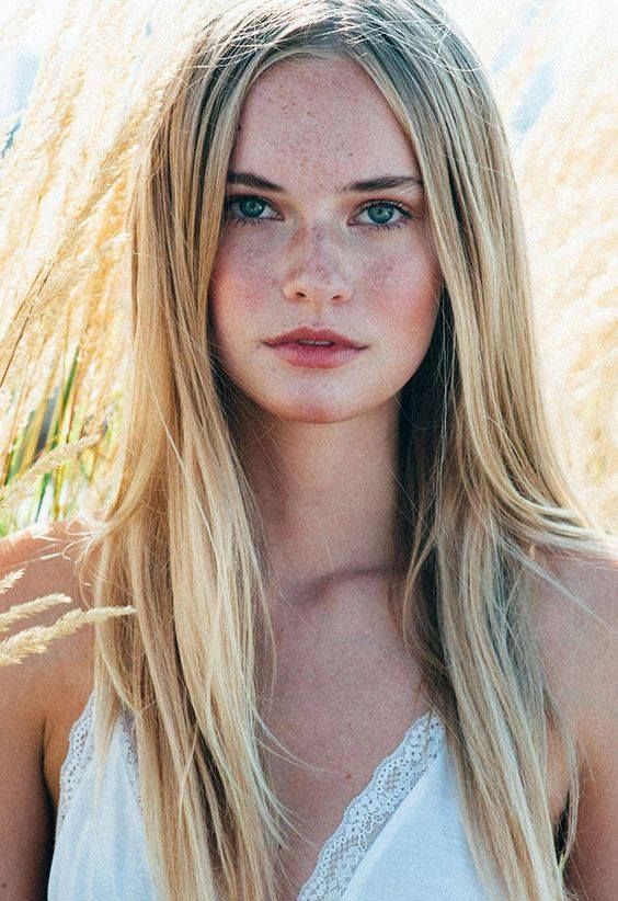 Woman with blonde hair and freckles in a white top outdoors