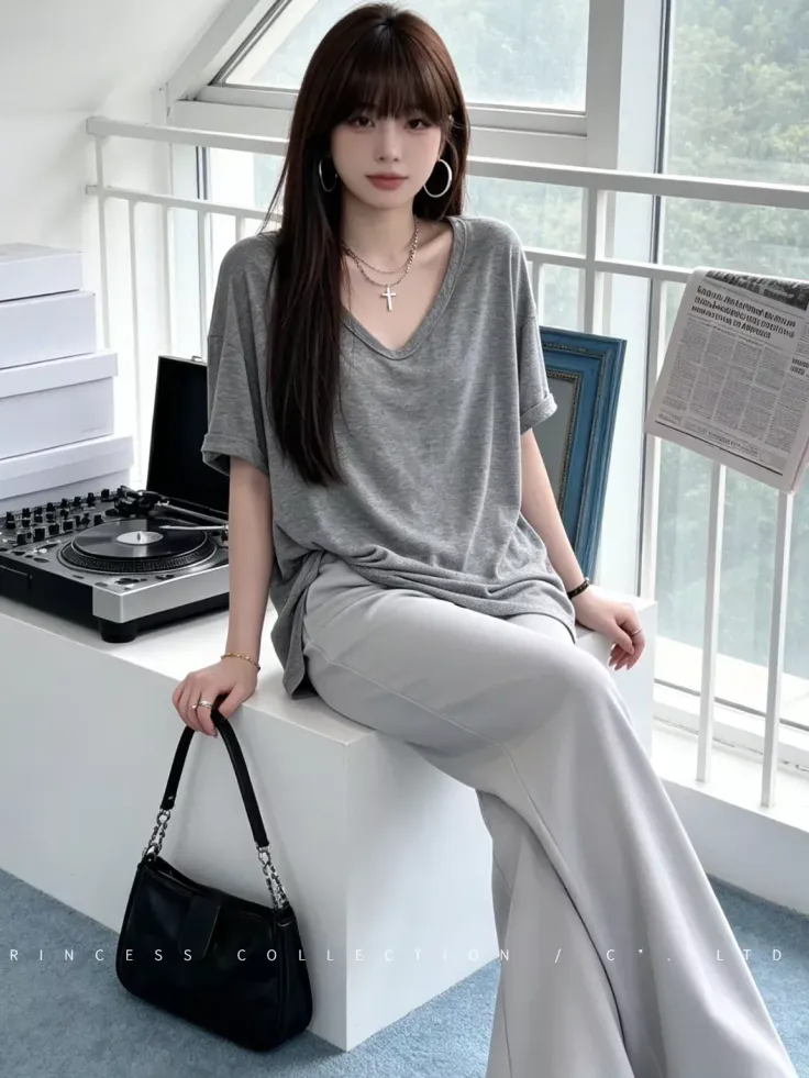 Woman with long hair wearing a gray t-shirt and wide leg pants indoors