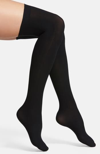 Pair of black thigh-high stockings on legs against a white background