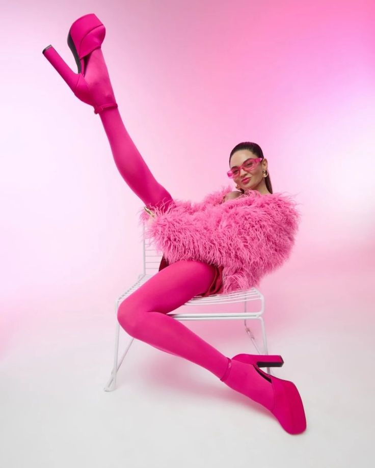 Woman in a vibrant pink furry jacket and tights striking a playful pose