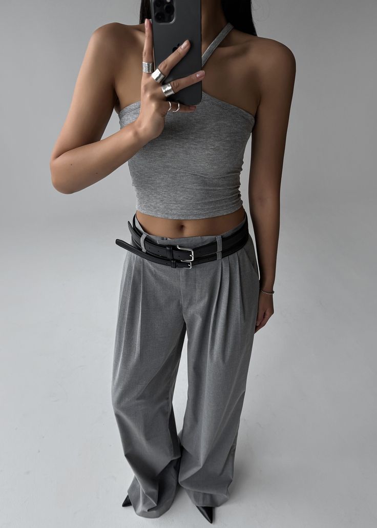 Person in a gray top and wide leg pants taking a mirror selfie