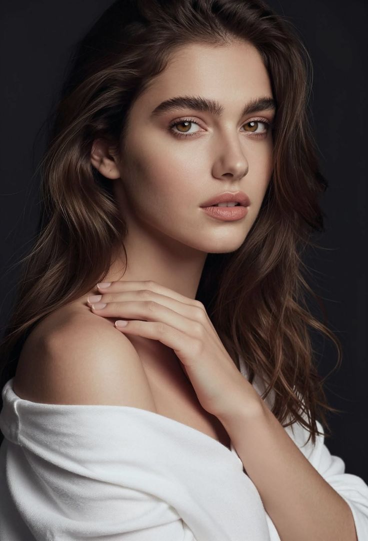Woman with long brown hair and a white shirt draped off her shoulders