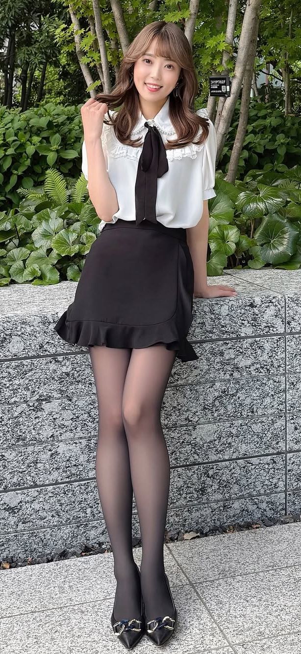 Woman in a white blouse and black skirt with black tights posing outdoors