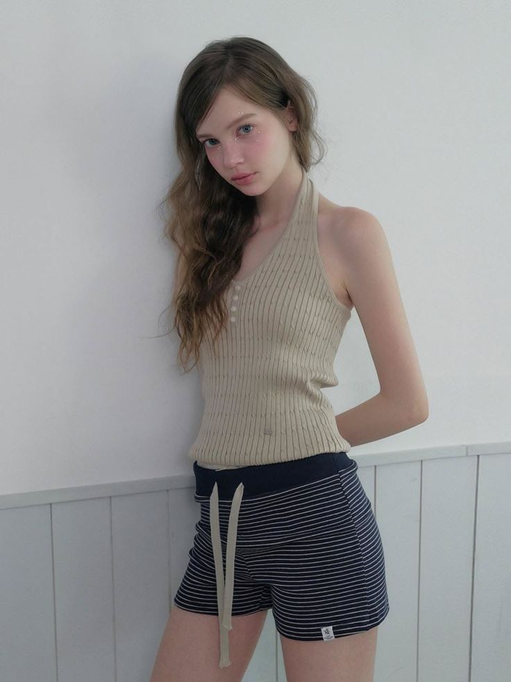 Woman with long hair wearing a halter top and striped shorts indoors