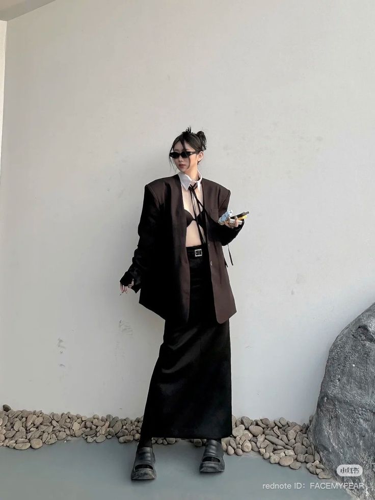 Woman in an oversized blazer, bra top, and long skirt posing outdoors