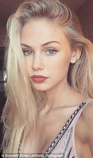 Blonde woman with blue eyes and pink top looking at the camera
