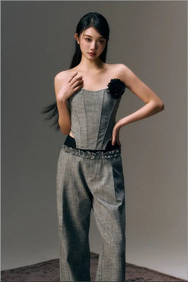 Woman in a gray corset top and matching pants with a black flower detail