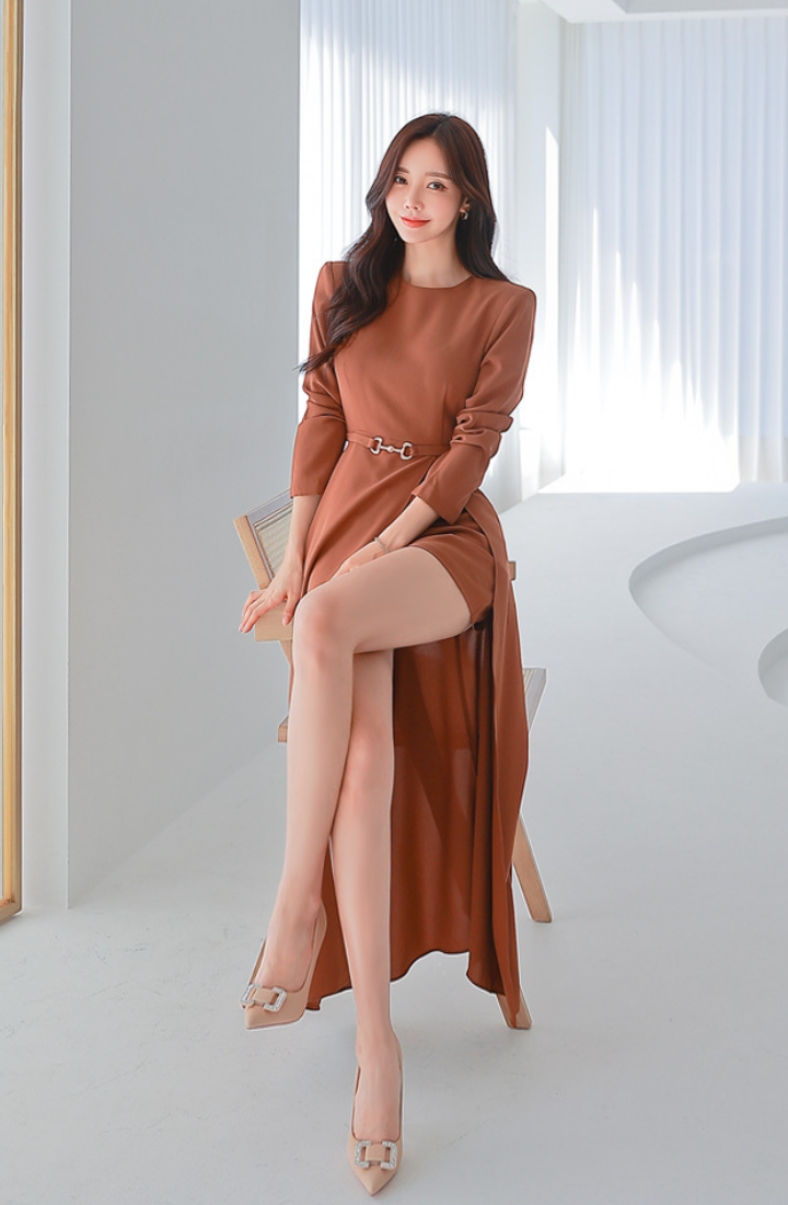 Woman in a long brown dress with a high slit, sitting indoors