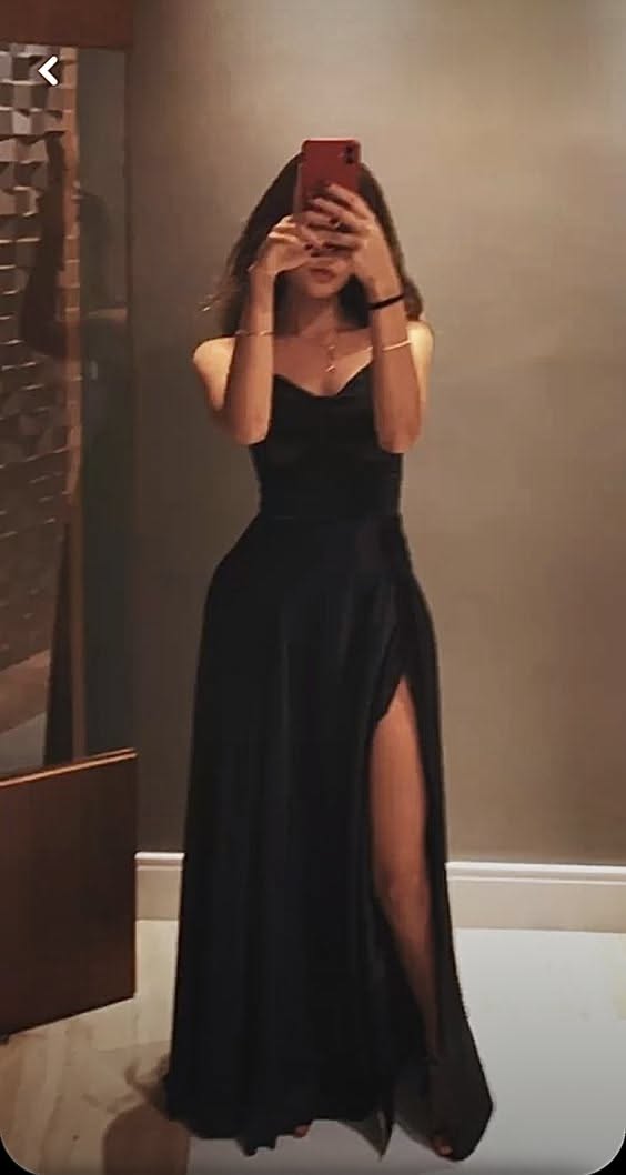 Woman in a black strapless dress with a high slit taking a mirror selfie