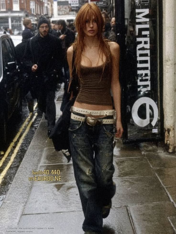 Woman in a tank top and distressed jeans walking on a wet street