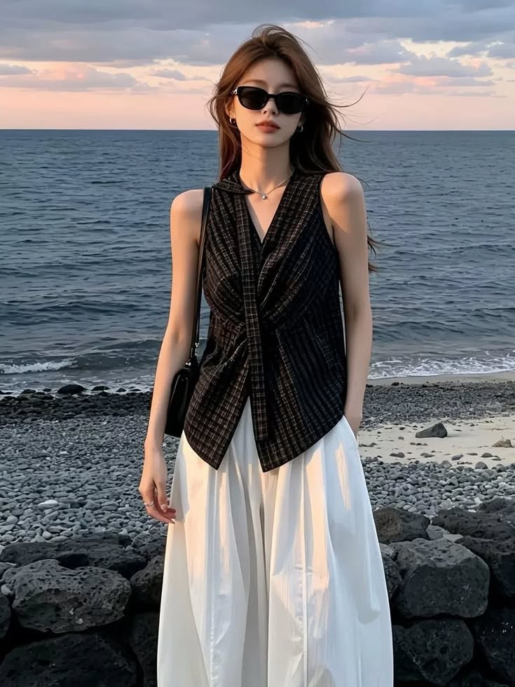 Woman with long hair and sunglasses on a rocky beach at sunset