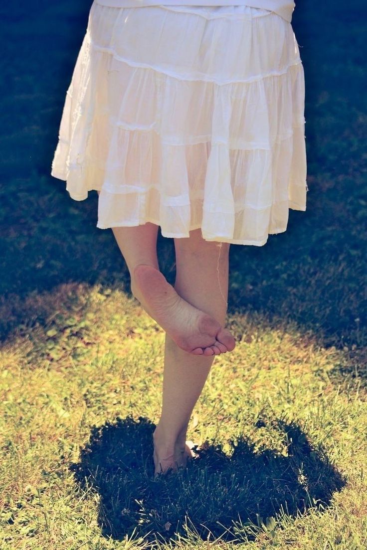 Person in a white skirt standing barefoot on grass