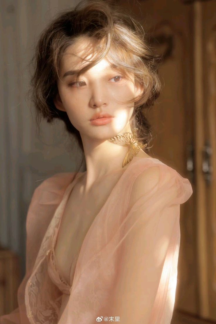 Woman in a pink dress with a butterfly necklace in soft golden hour light