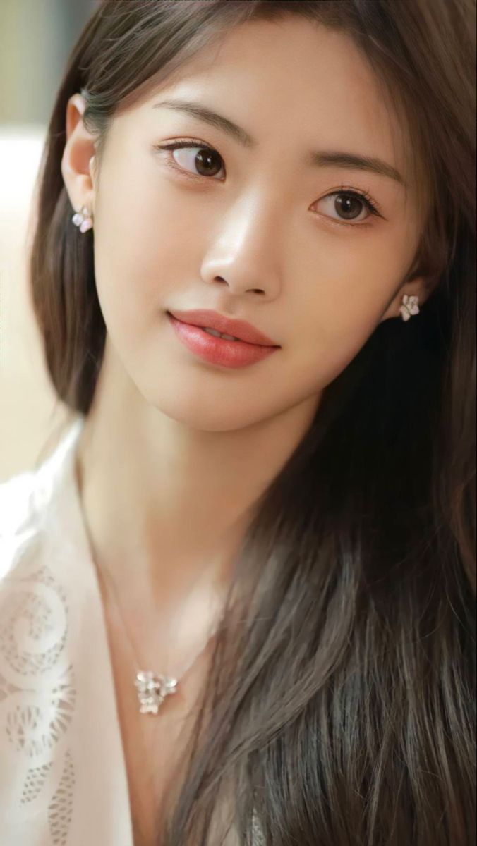 Woman with long brown hair wearing a white top and jewelry