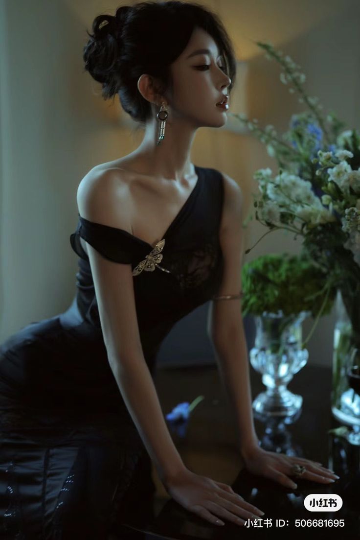 Woman in a black dress with an updo hairstyle posing indoors