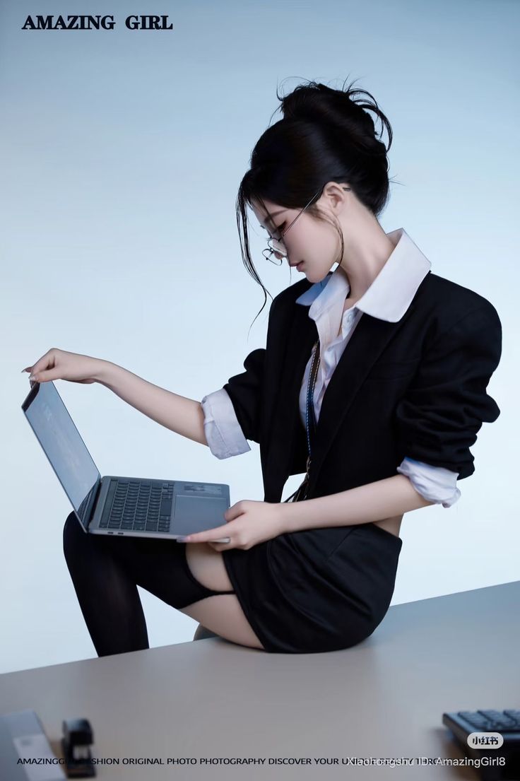 Woman in a blazer and mini skirt with stockings, sitting and using a laptop