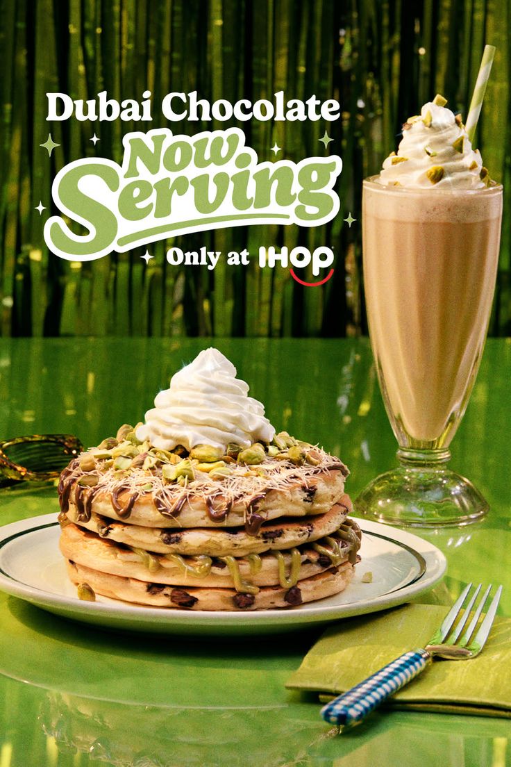 Stack of pancakes with whipped cream and pistachios next to a milkshake