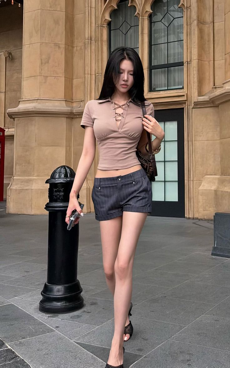Woman with long black hair wearing a cropped top and short shorts on a city street