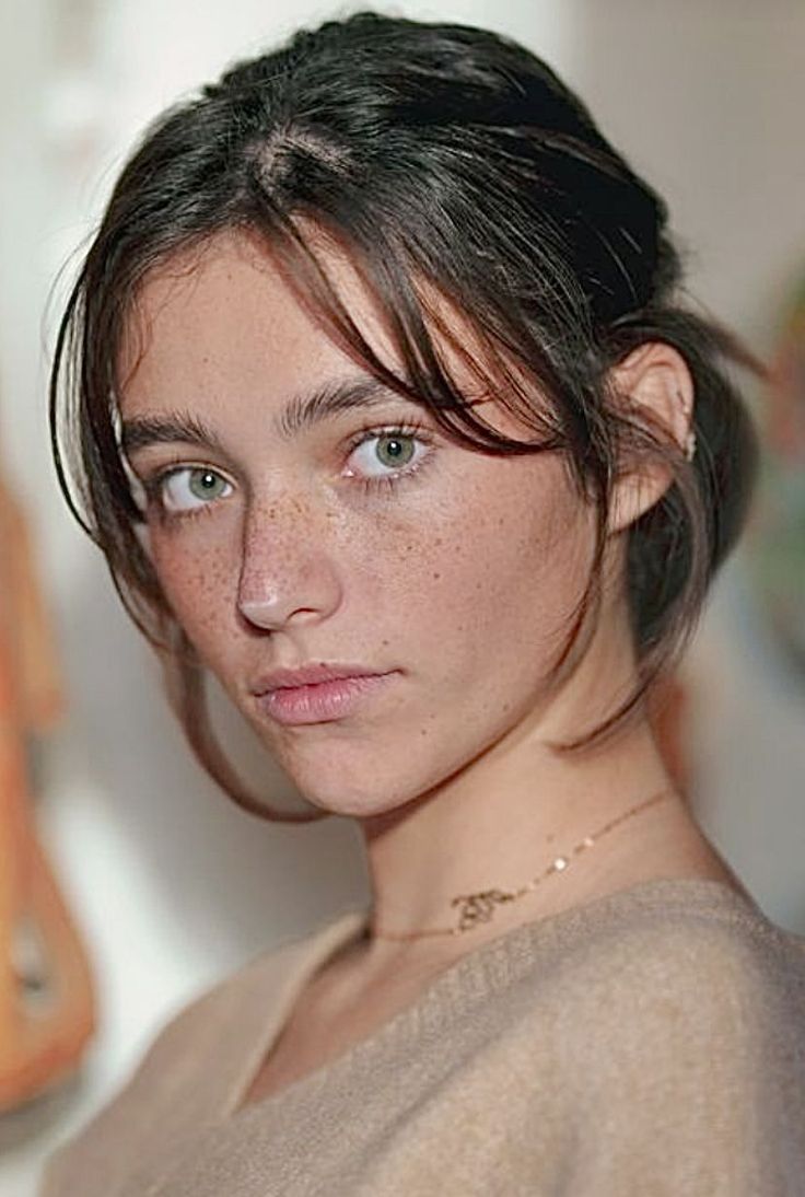 Woman with freckles and green eyes wearing a delicate necklace