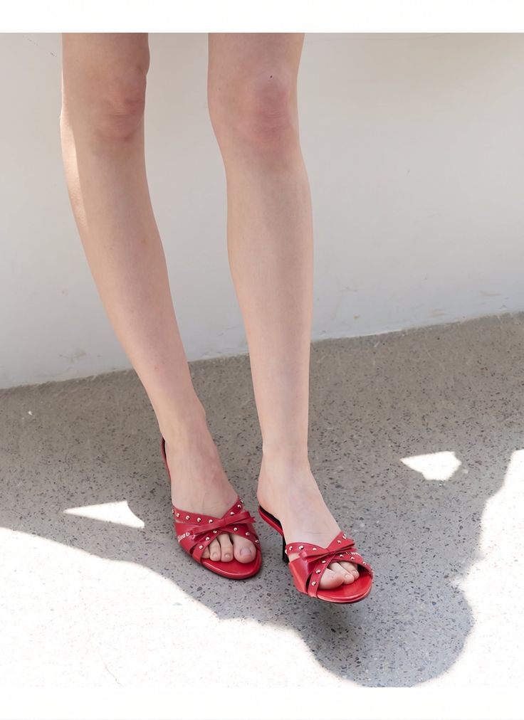 Woman's legs and feet in red studded sandals with bows