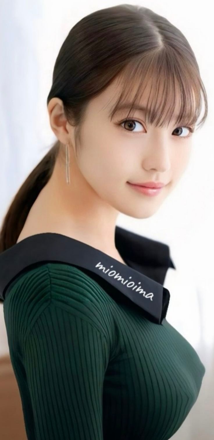 Woman with a ponytail and bangs wearing a green off-shoulder top