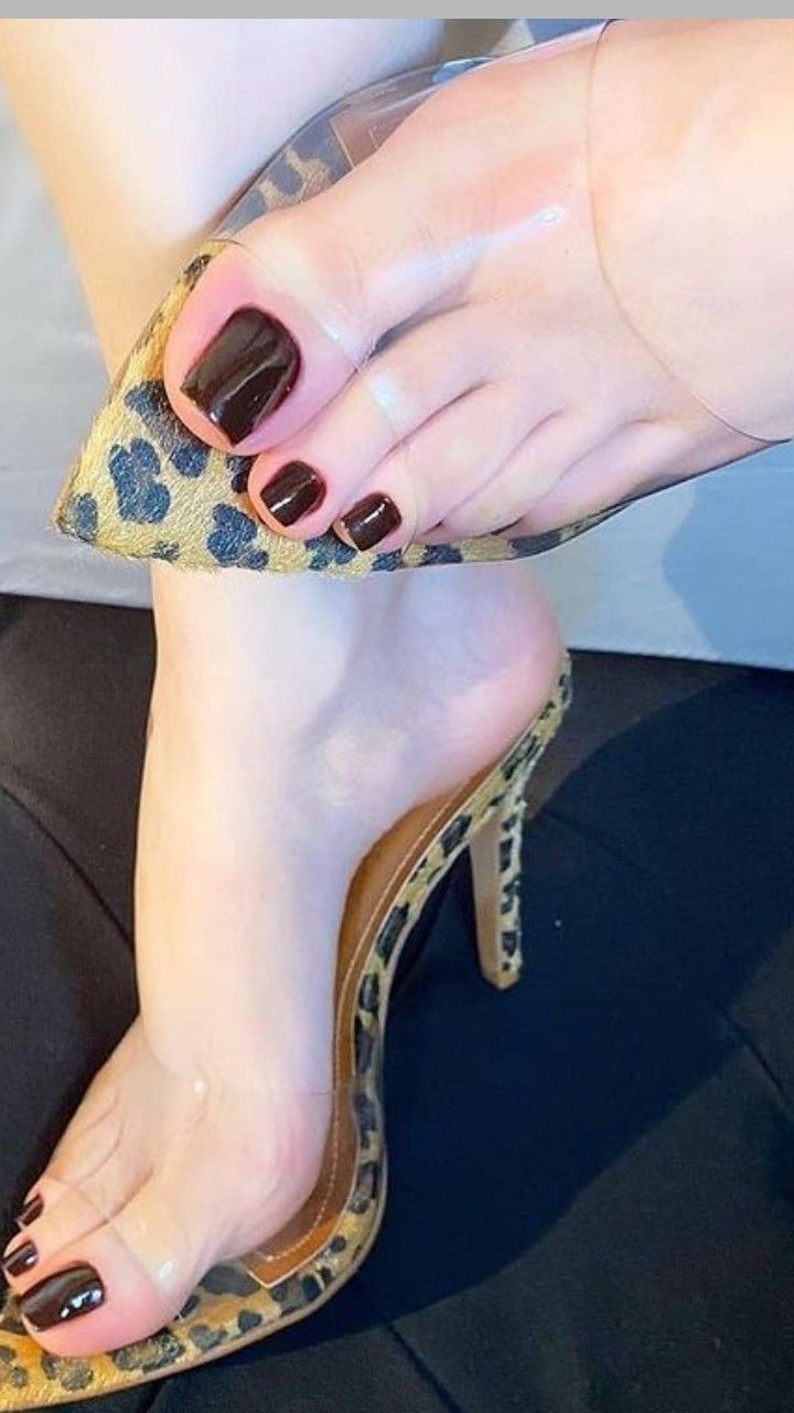Foot wearing a leopard print high heel with dark nail polish