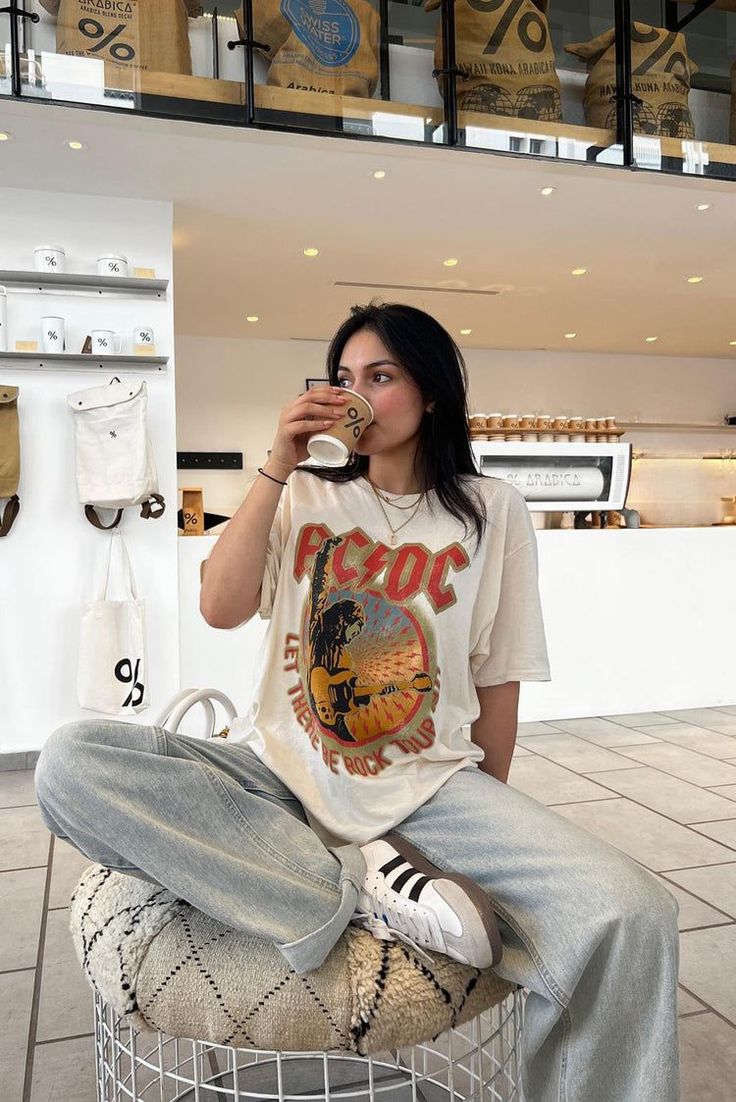 Woman in an oversized t-shirt and loose jeans sitting in a coffee shop