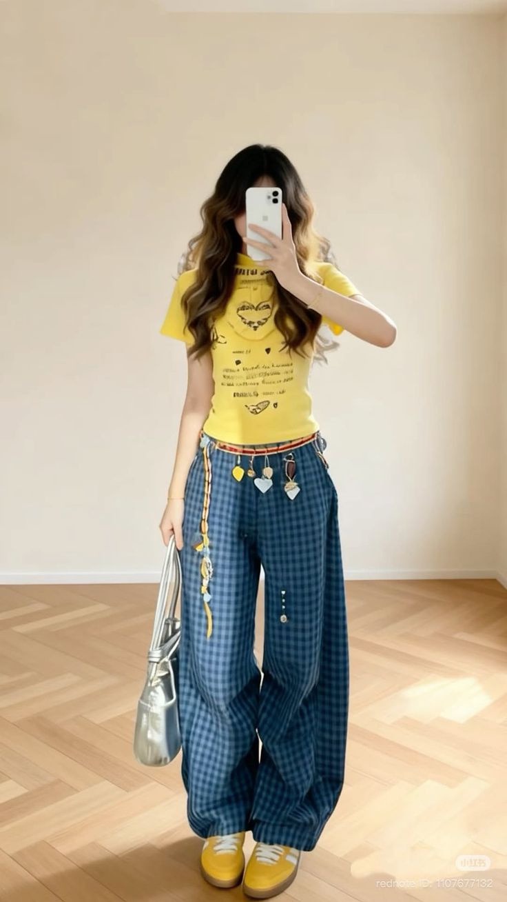 Person in a yellow t-shirt and plaid pants taking a mirror selfie