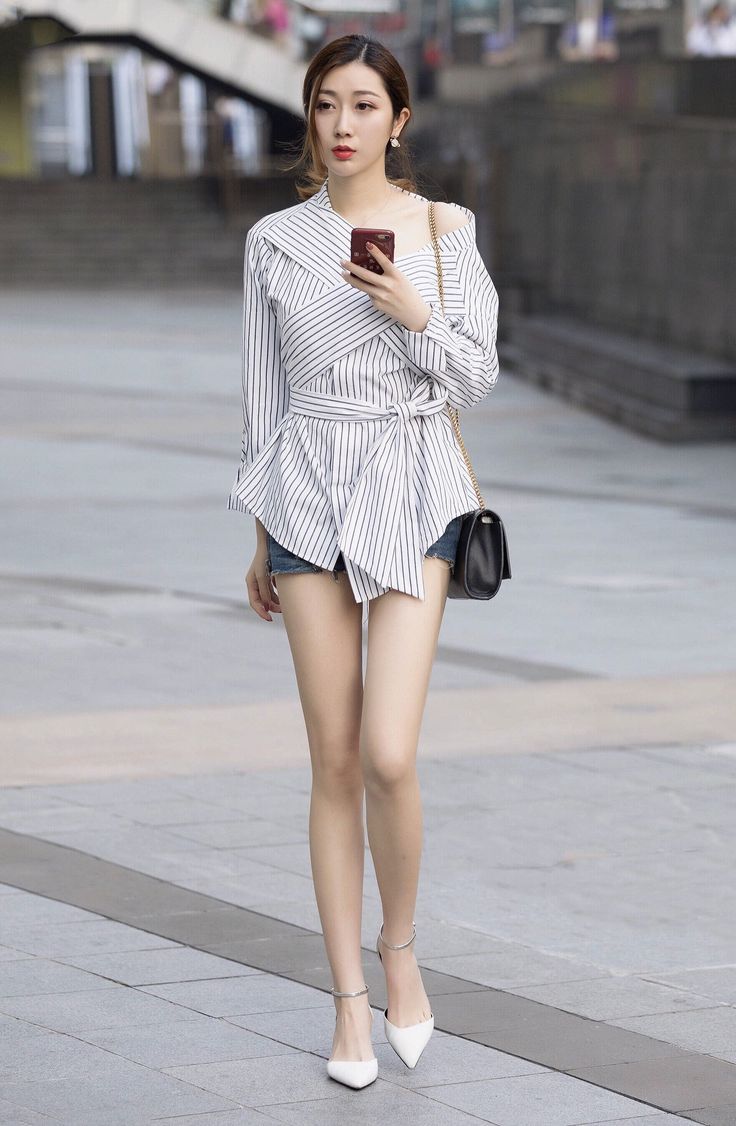 Woman in a striped top and denim shorts walking on a street