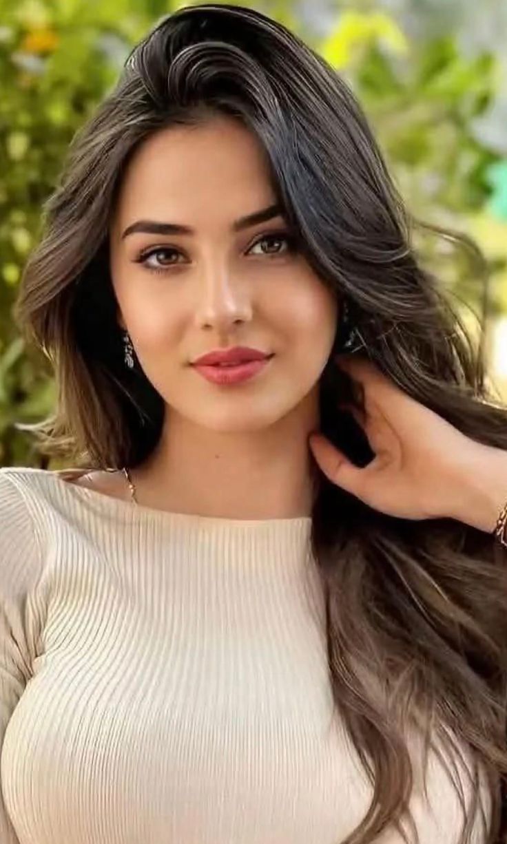 Woman with long brown hair wearing a ribbed top and earrings outdoors