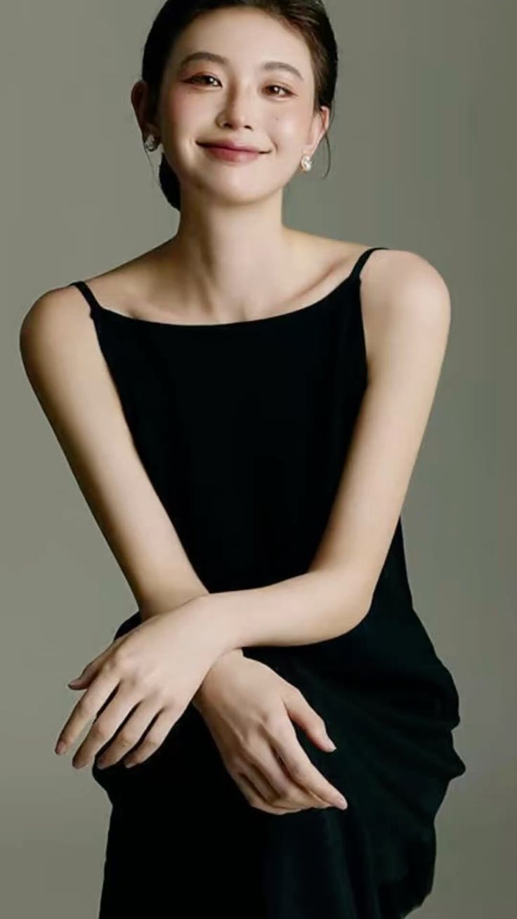 Woman in a black dress with short hair and earrings, smiling at the camera