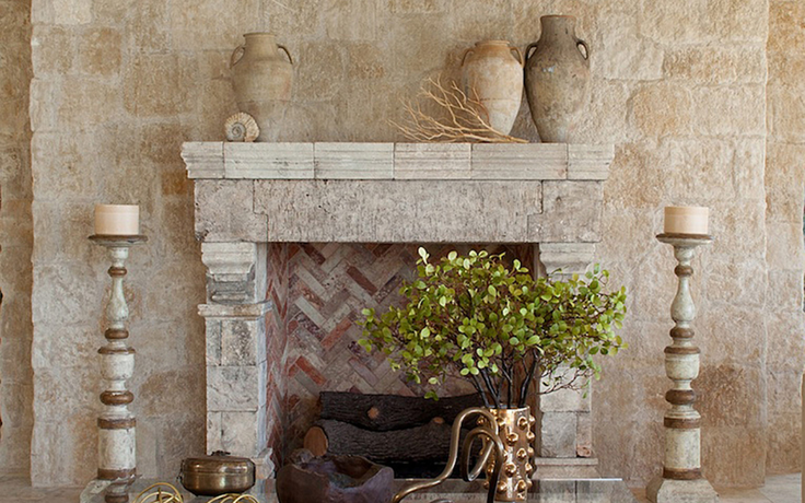 Stone fireplace with decorative vases, candlesticks, and green foliage
