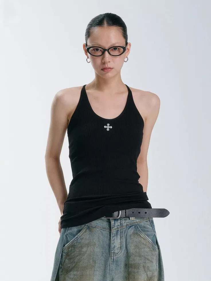 Woman in a black tank top and denim skirt with glasses and slicked back hair