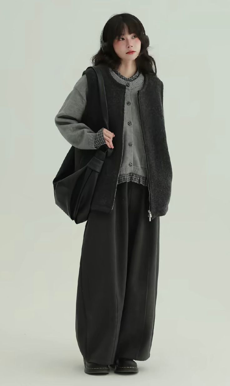 Woman with long hair wearing headphones, a cardigan, and wide leg pants