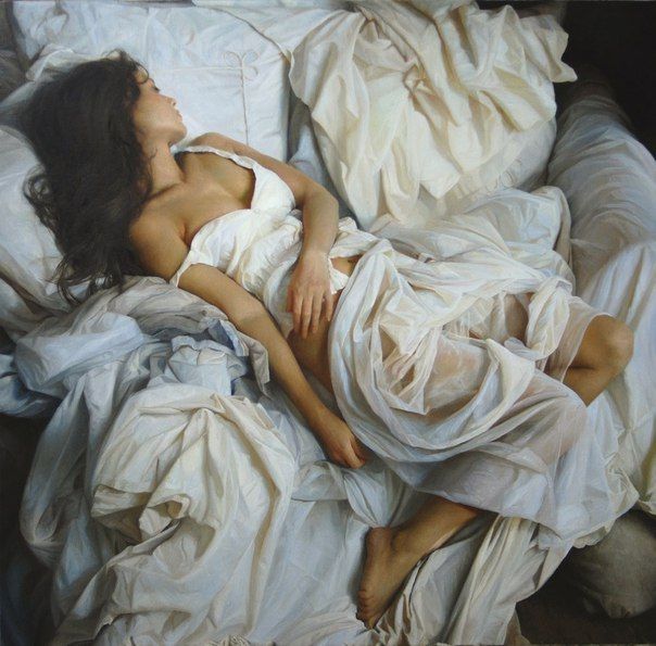 Woman with long hair lying on white sheets in a bedroom