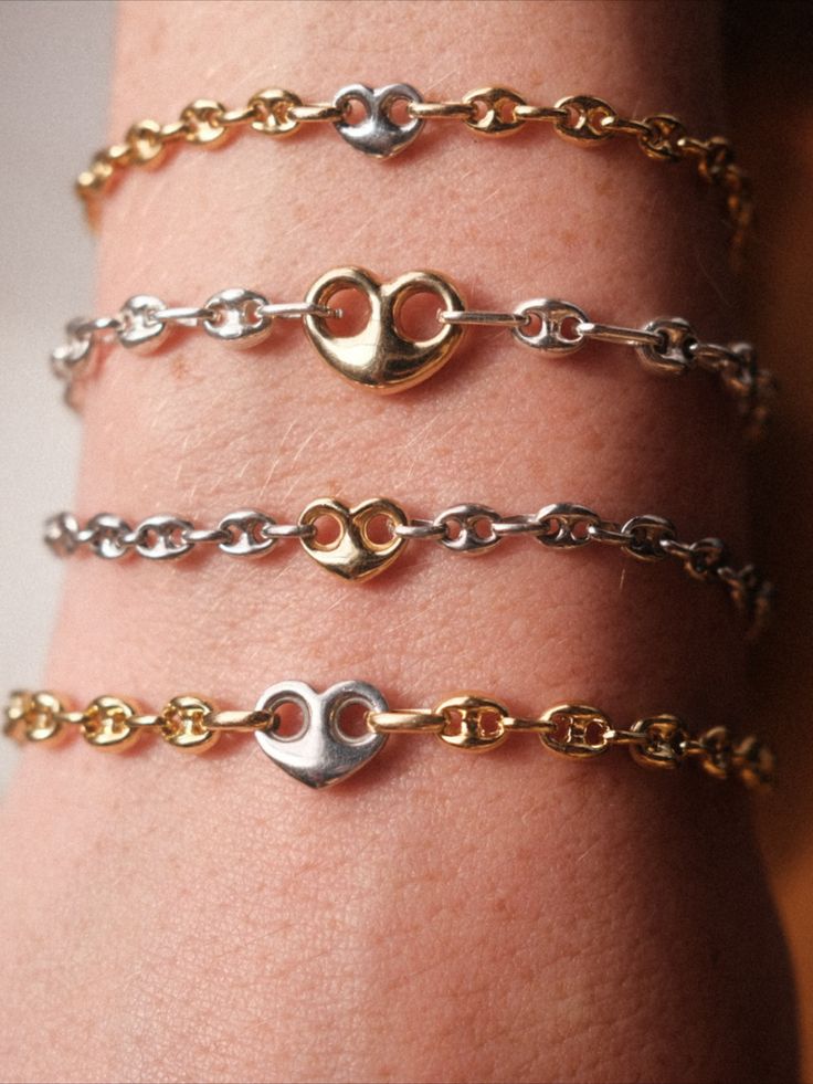Four bracelets with heart-shaped charms on an arm