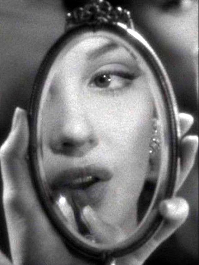 Woman's face reflected in a hand mirror, black and white photograph