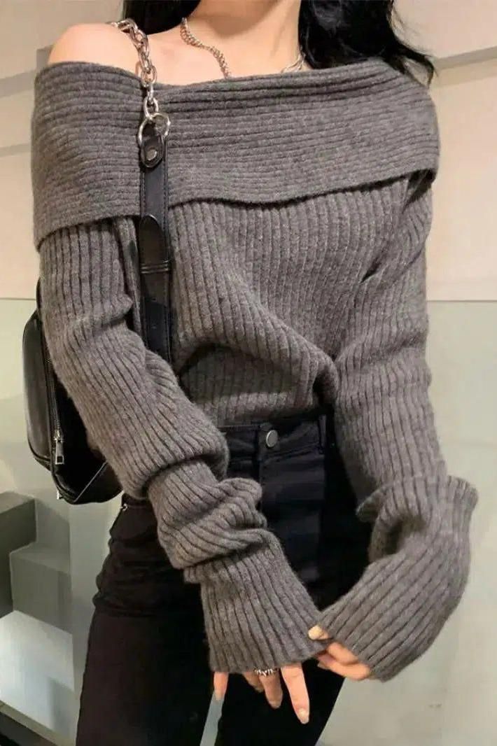 Person wearing a gray off-shoulder ribbed knit sweater and black pants