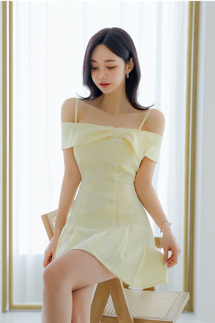 Woman in a yellow off-shoulder dress sitting indoors with soft lighting
