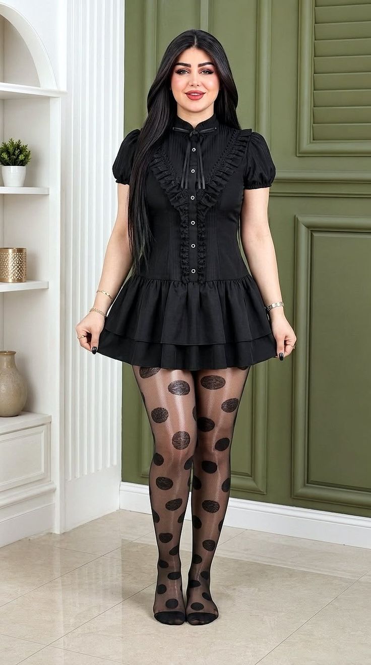 Woman in a black dress and polka dot tights standing indoors