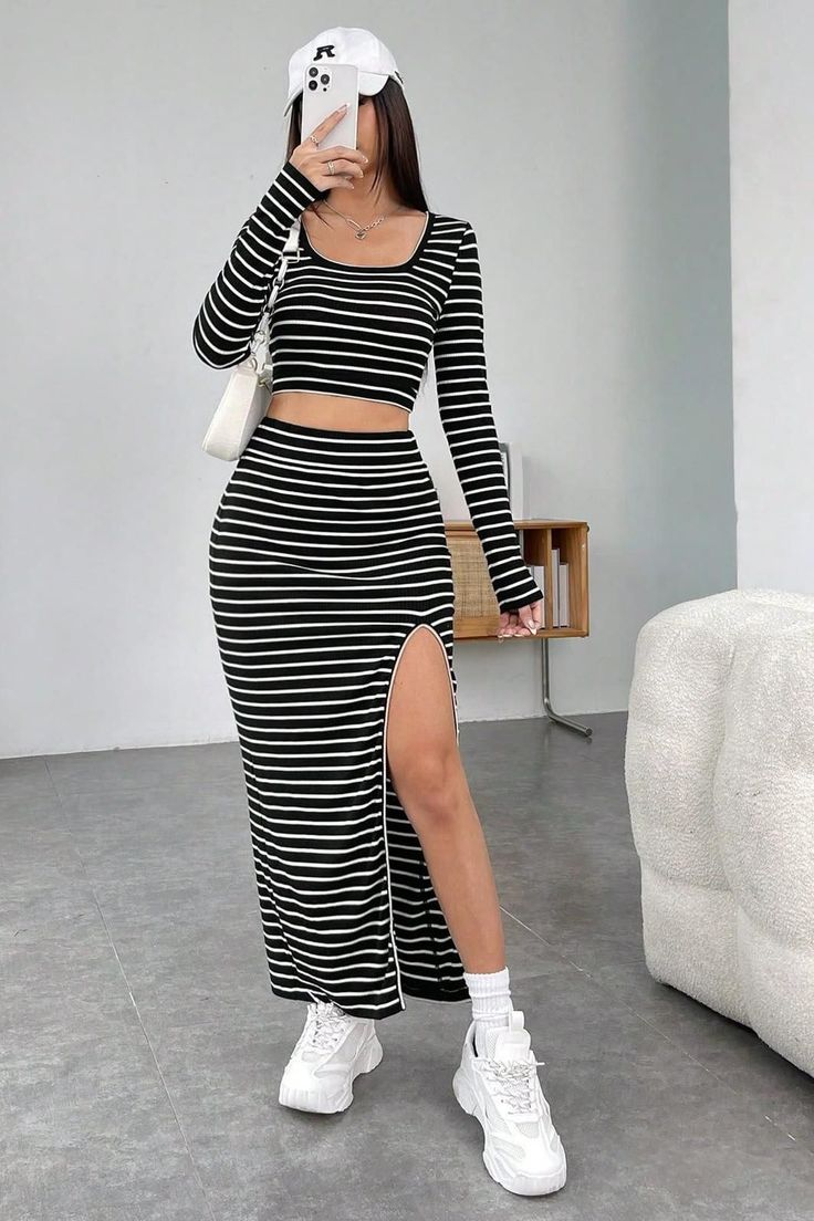 Woman in a black and white striped crop top and maxi skirt with a high slit