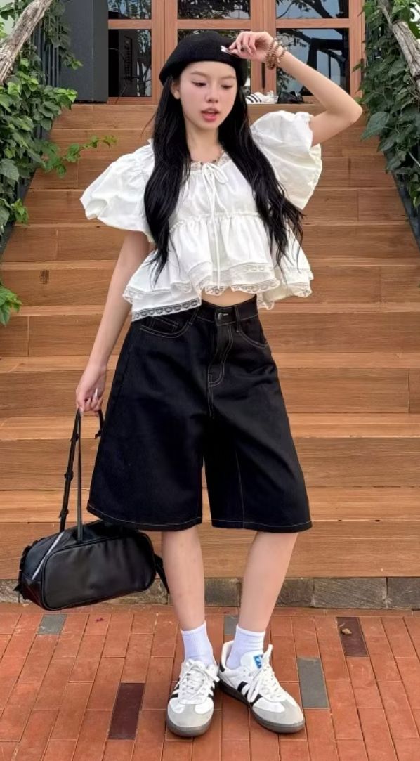 Woman in a white top, black shorts, and beret standing outdoors