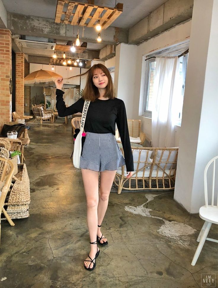 Woman in a black top and gingham shorts walking in a cafe