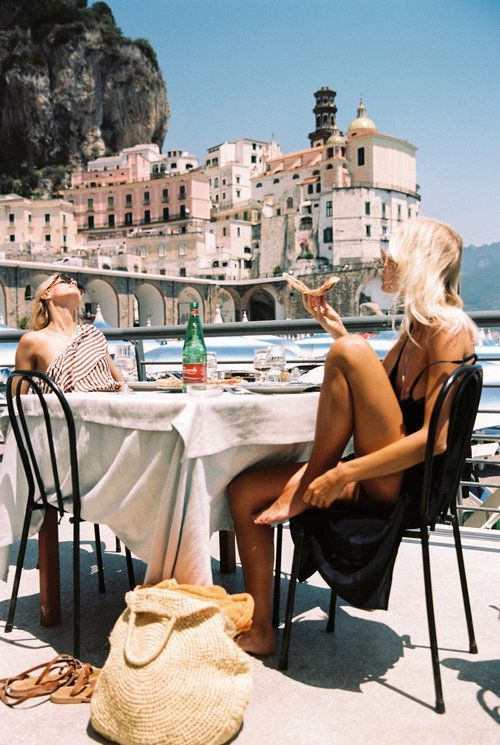 Two women dining outdoors with a scenic view of the Amalfi Coast
