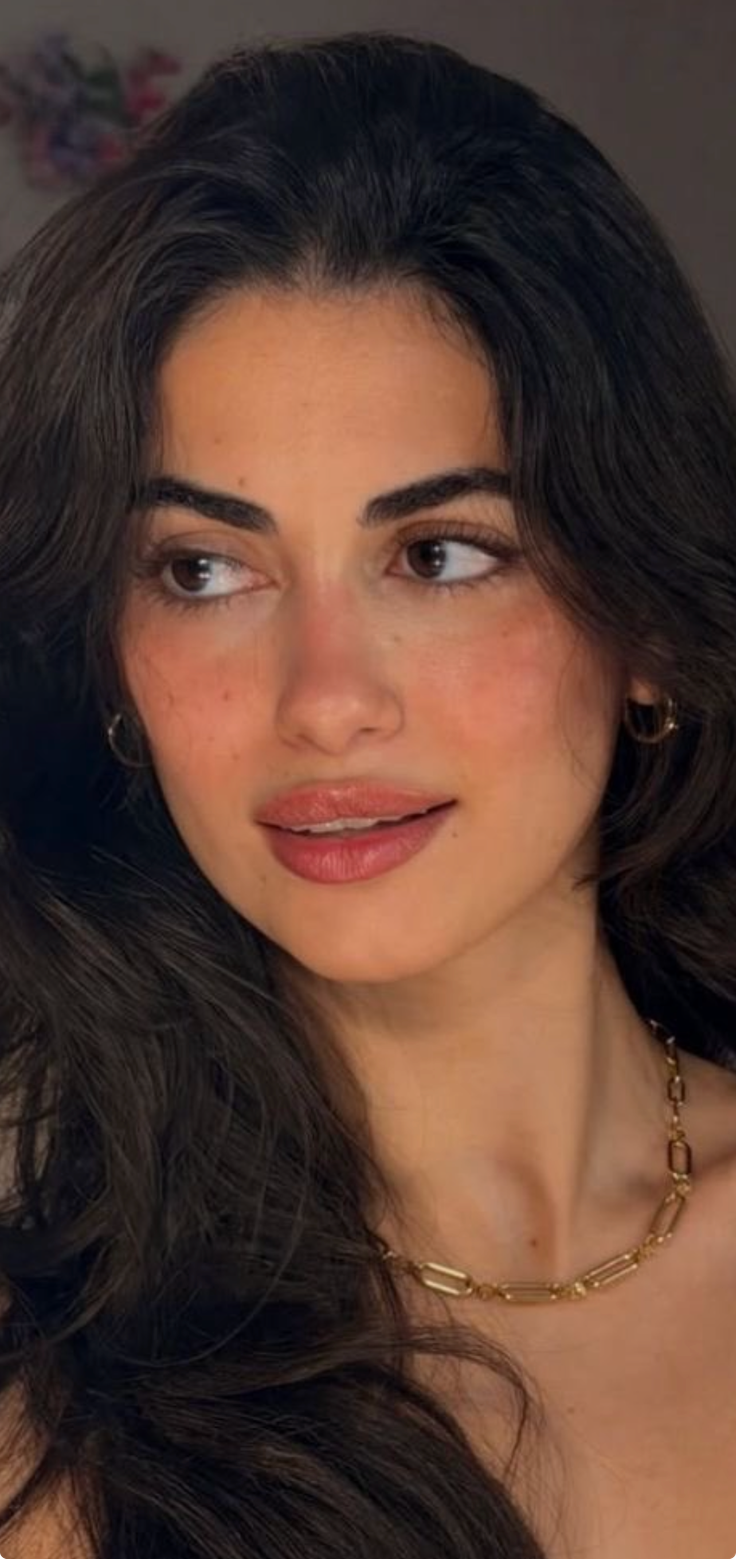 Woman with long dark hair and gold jewelry looking to the side