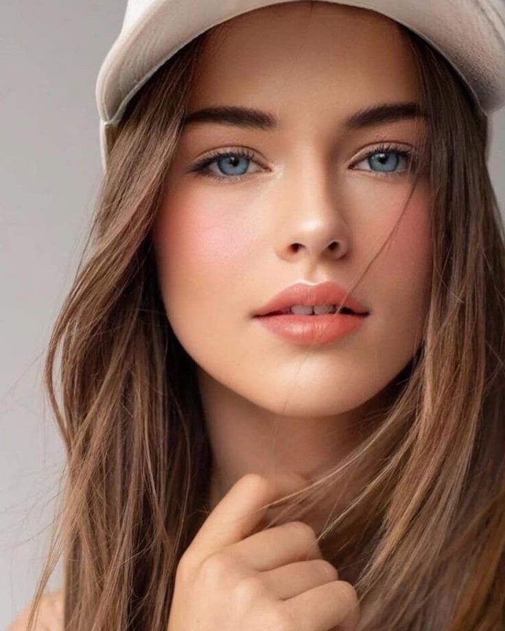 Woman with blue eyes and long brown hair wearing a white hat