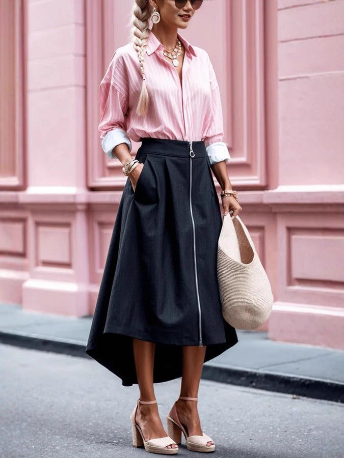 Woman with braided blonde hair wearing a pink shirt and black skirt outdoors