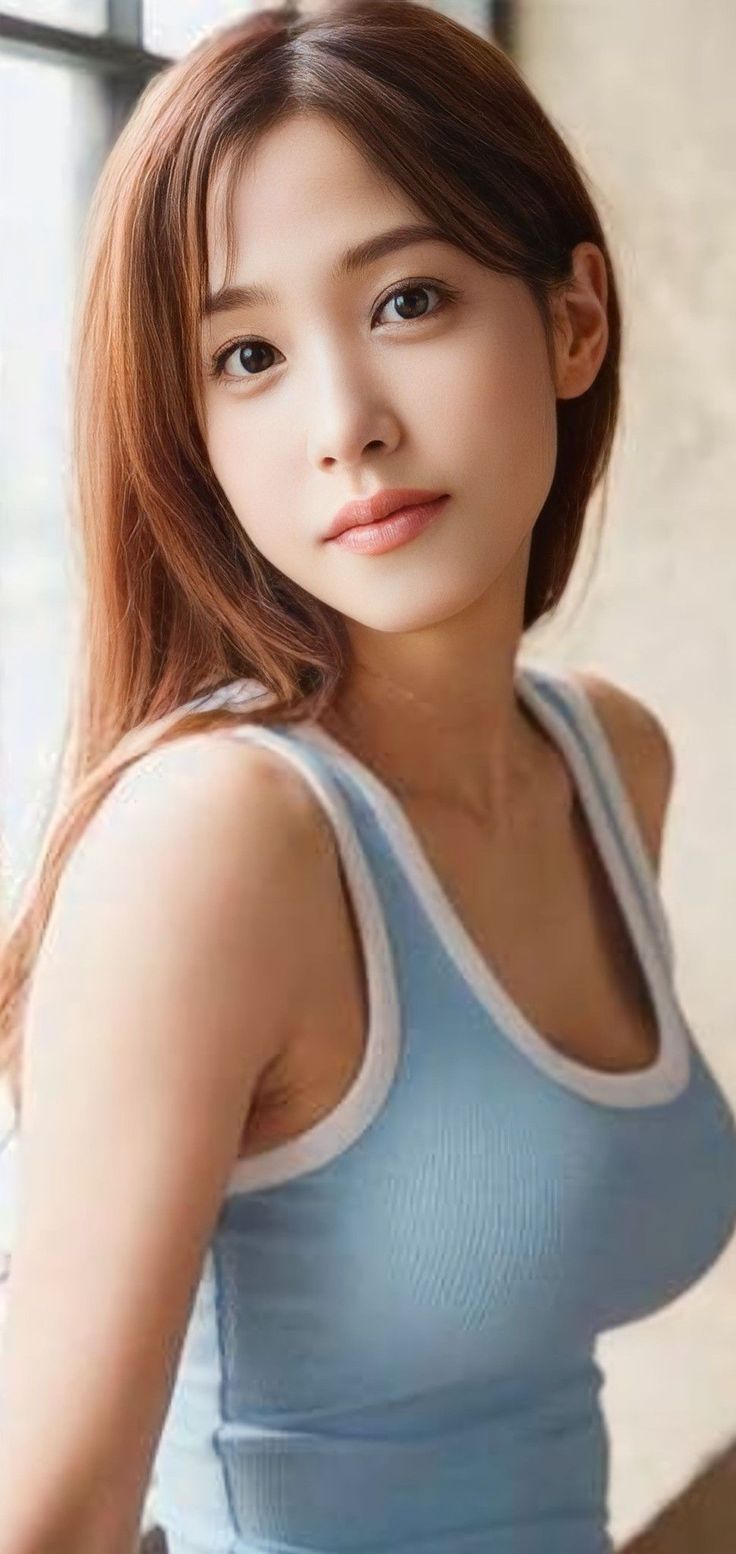 Woman with long light brown hair wearing a blue tank top indoors